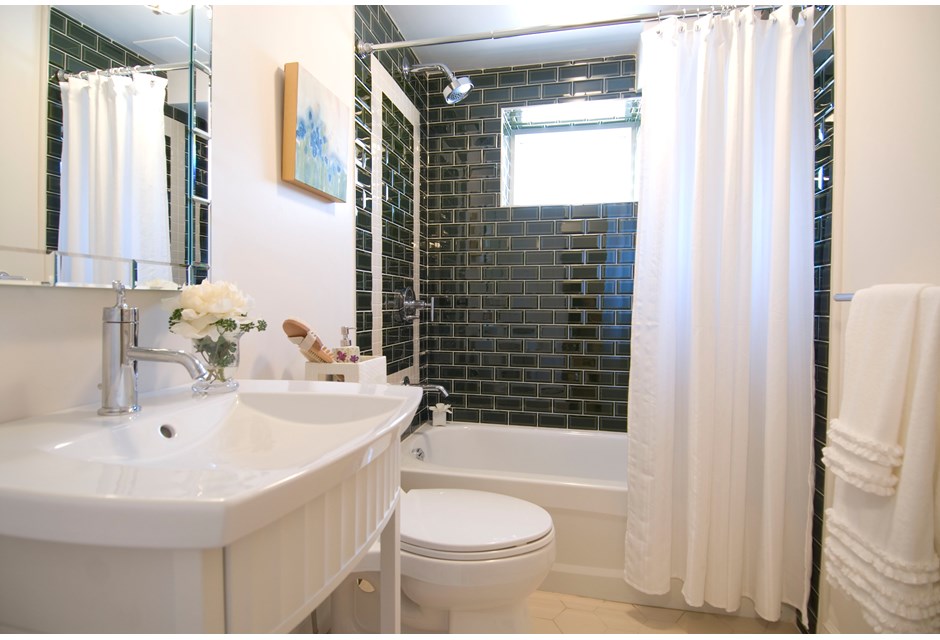 white bathroom with green subway tile in shower