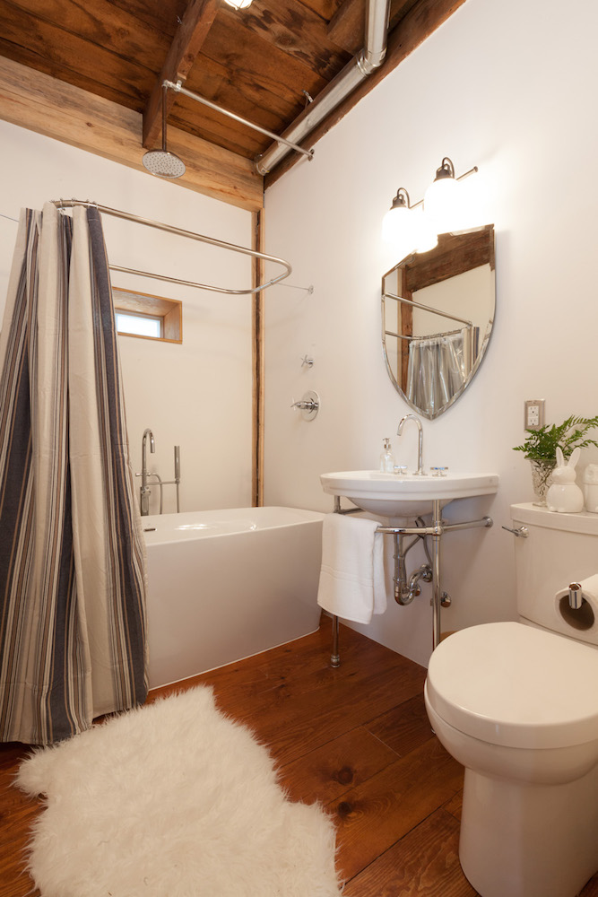 rustic white bathroom with pedestal sink and wooden floor