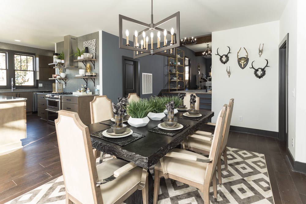black hanging light fixture above black dining table in rustic grey dining room