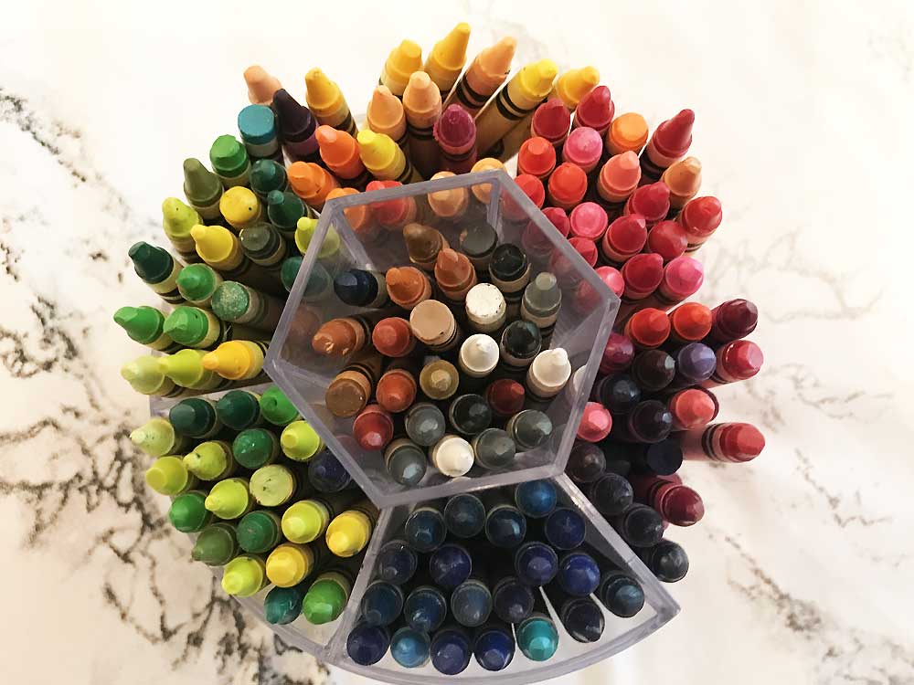 organized crayons in divided compartments on marble surface