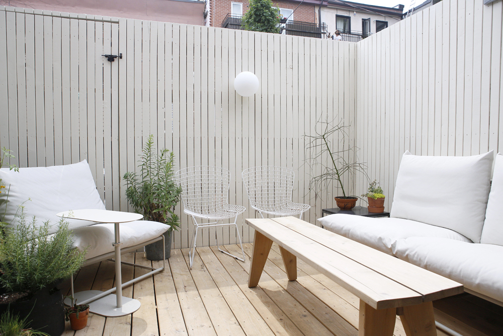 white outdoor deck with white vertical fencing, wooden bench, white furniture