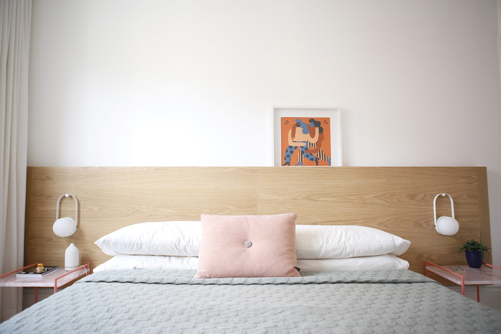 wooden bed with orange artwork on it, pink cushion