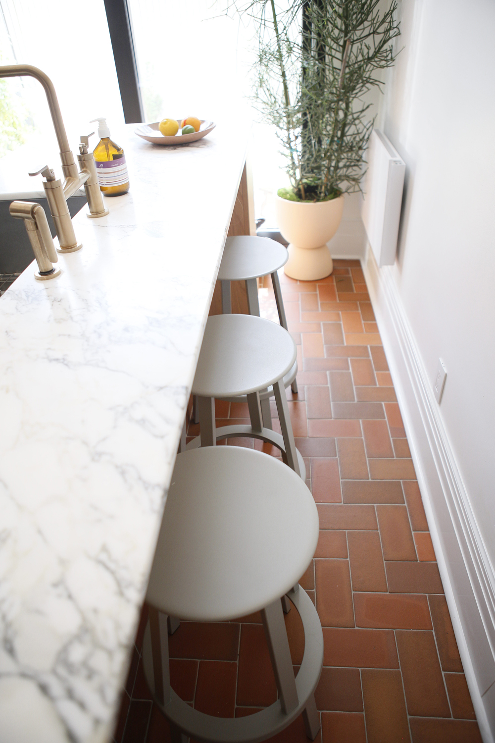marble island with three pale stools and brass faucet