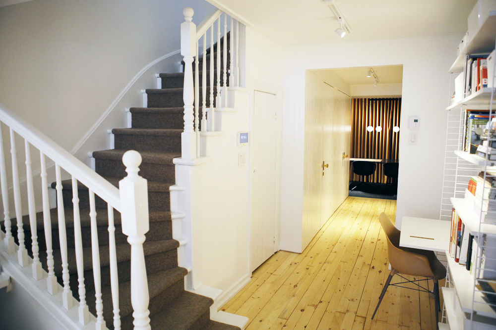 white turning staircase with grey runner, wood floors. white shelves and desk