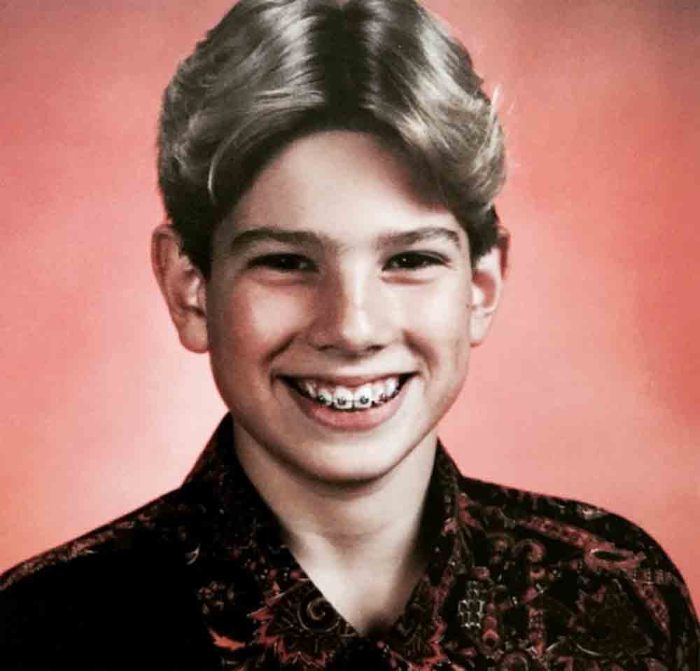 A pre-teen Scott McGillivray smiling in a portrait picture with braces on his teeth.