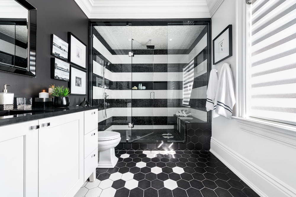 Black and white designed master ensuite bathroom with black and white striped accent wall in shower.