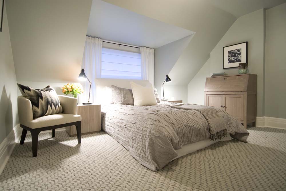 A bedroom in a converted attic space, with big comfy bed and stylish bedding.