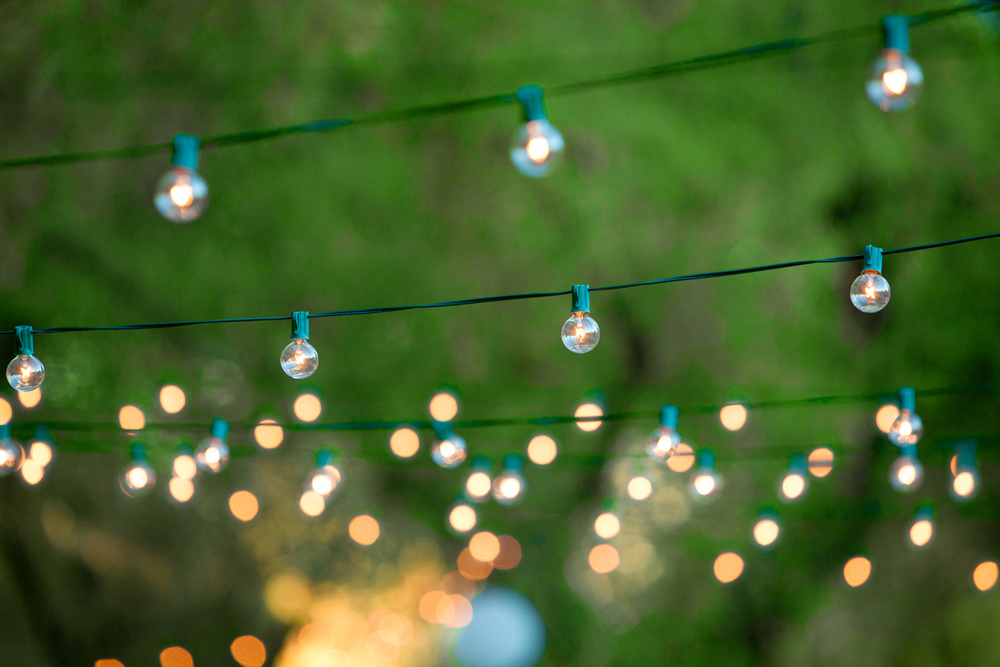 Lots of overhead white fairy lights on green wire, with background fading.