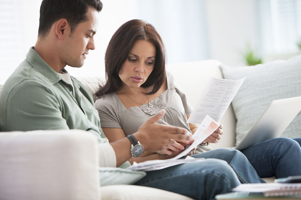 couple looking at papers while sitting on couch