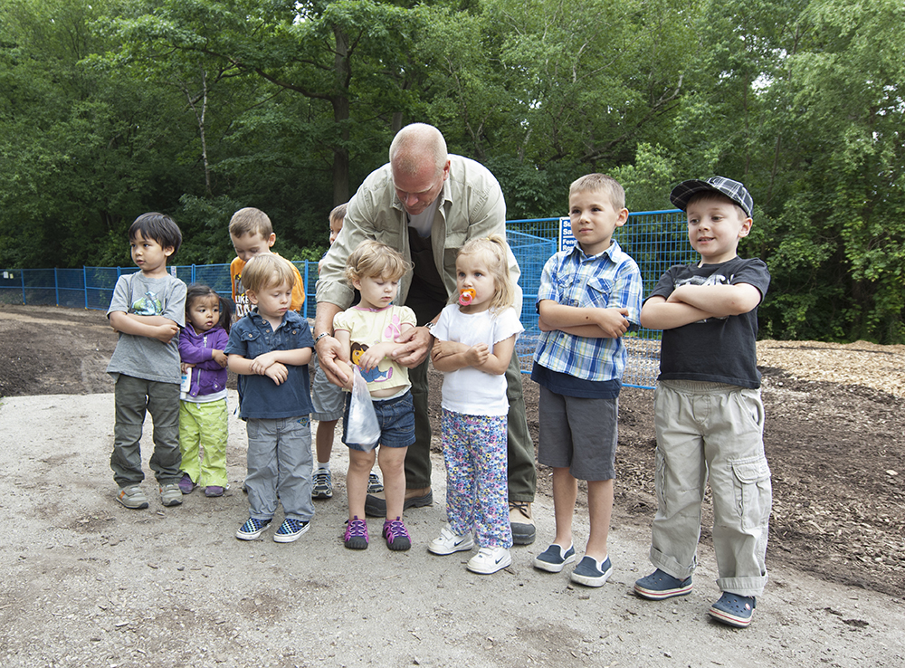 Mike Holmes standing with a group kids who are doing his signature arms-crossed pose