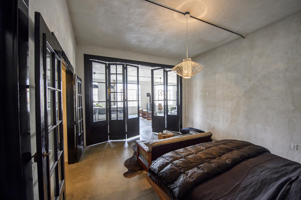 An industrial-style bedroom with one exposed beam and unique light fixture