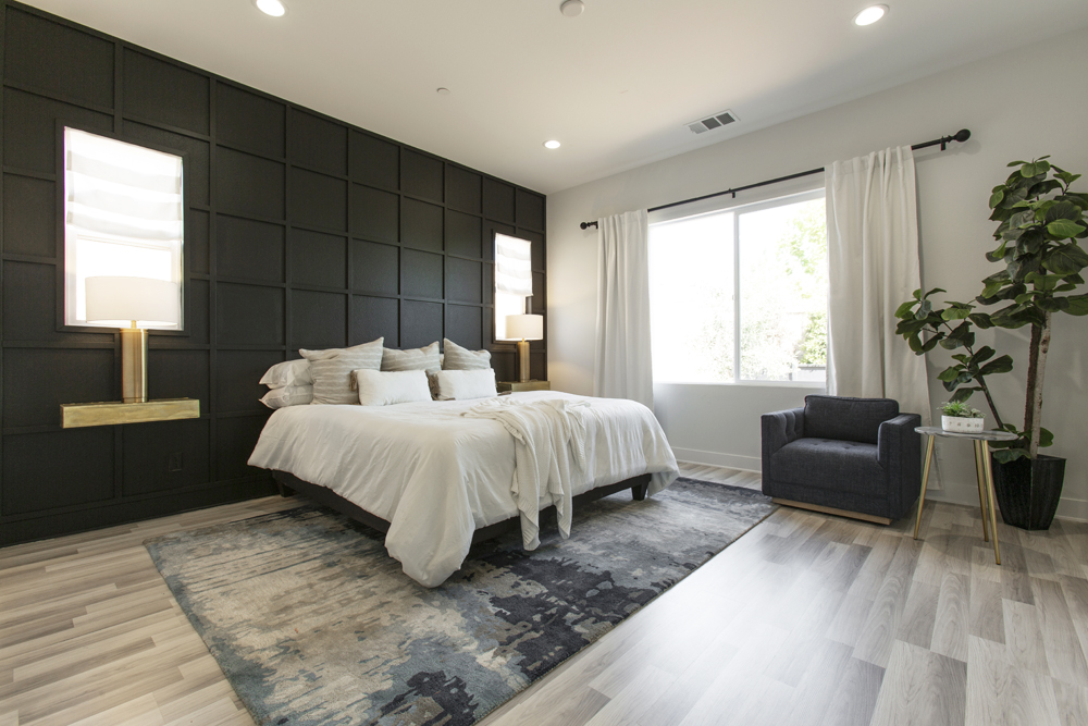 A large master bedroom with area rug and unique mirrors, lights and side tables