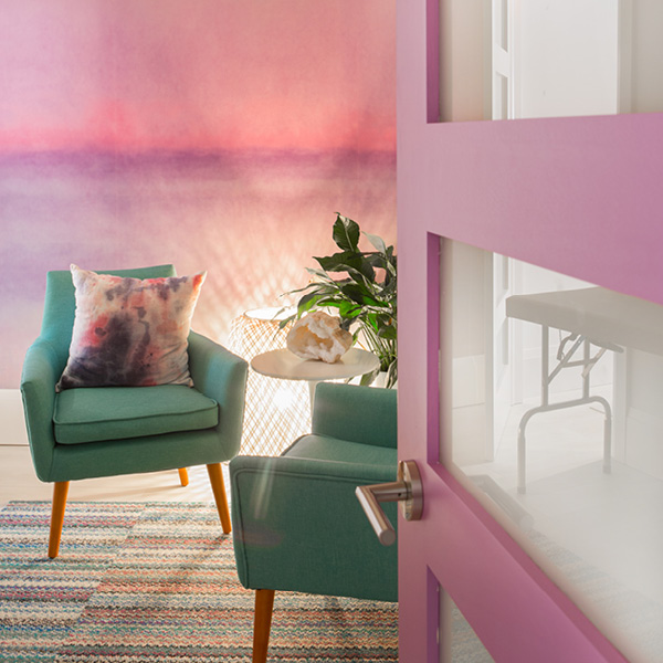 Pink door opening to waiting room with pink ombre wall art