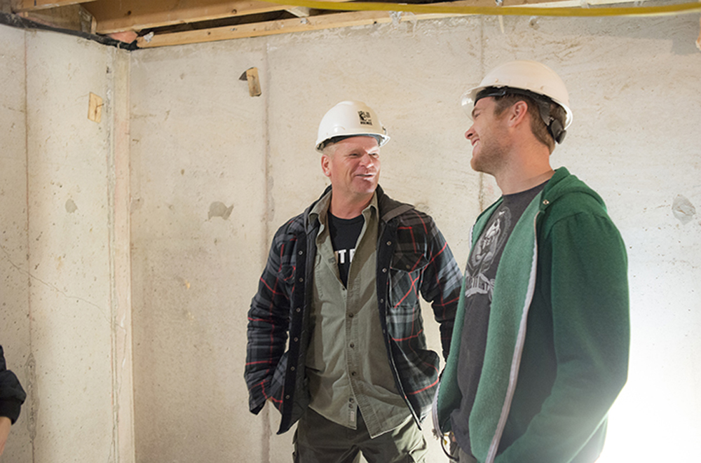 Mike Holmes and Mike Holmes Jr. in unfinished basement