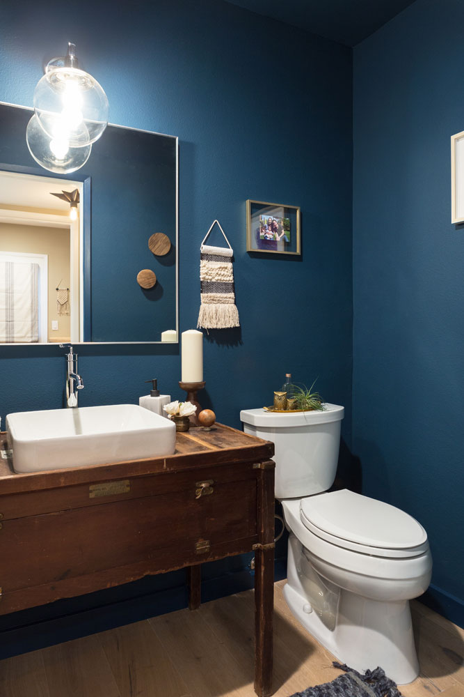 Powder room with repurposed antique chest as vanity and navy blue walls.