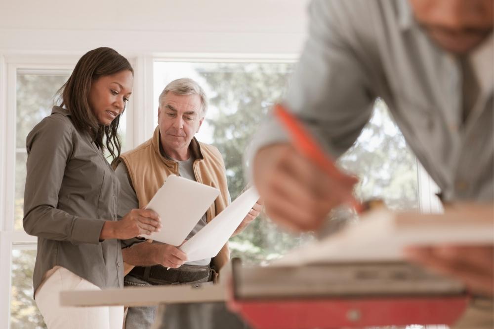 A woman speaking with her general contractor and viewing a document
