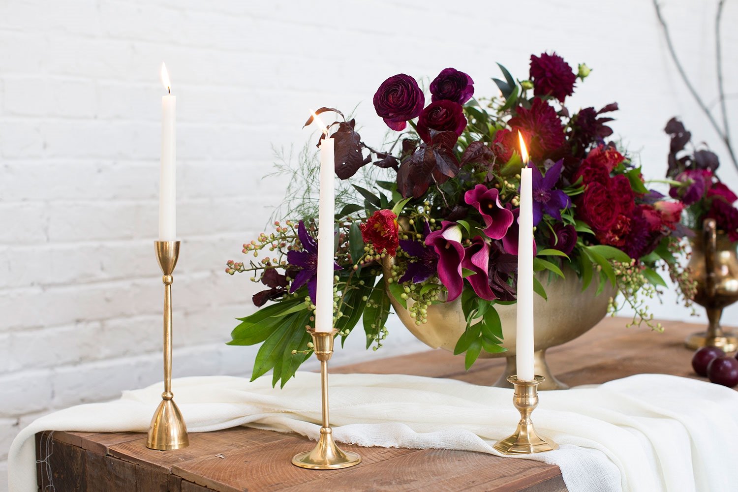 Brass candlesticks on a table with a purple and pink bouquet