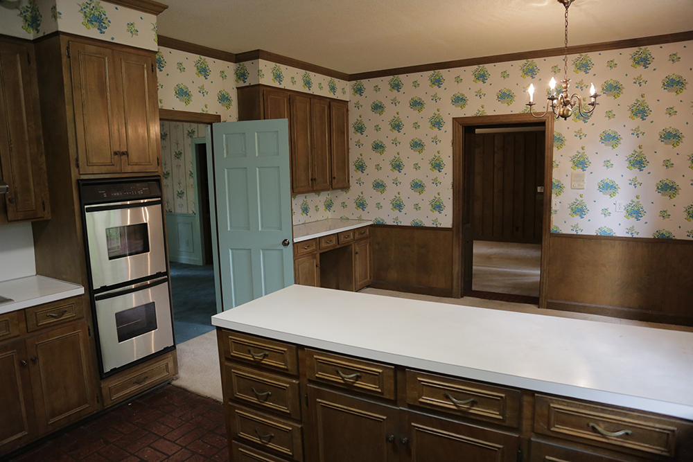 A 1970s kitchen with dark wood and tacky wallpaper