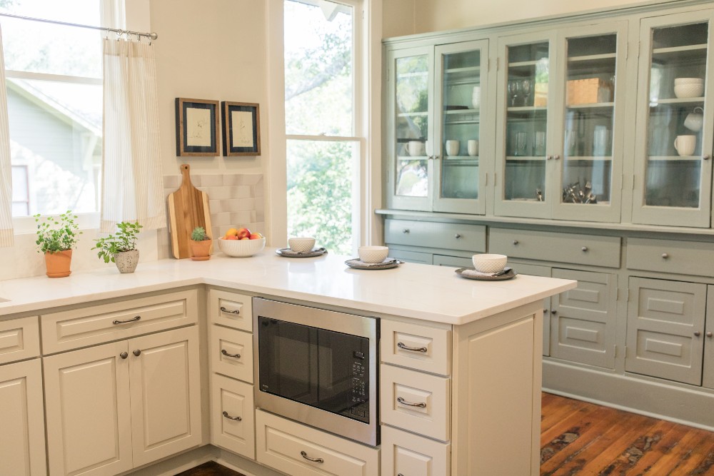 A mint green butler's pantry with glass cabinet doors
