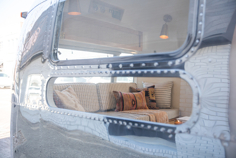 View through Airstream window of built-in couch with pillows