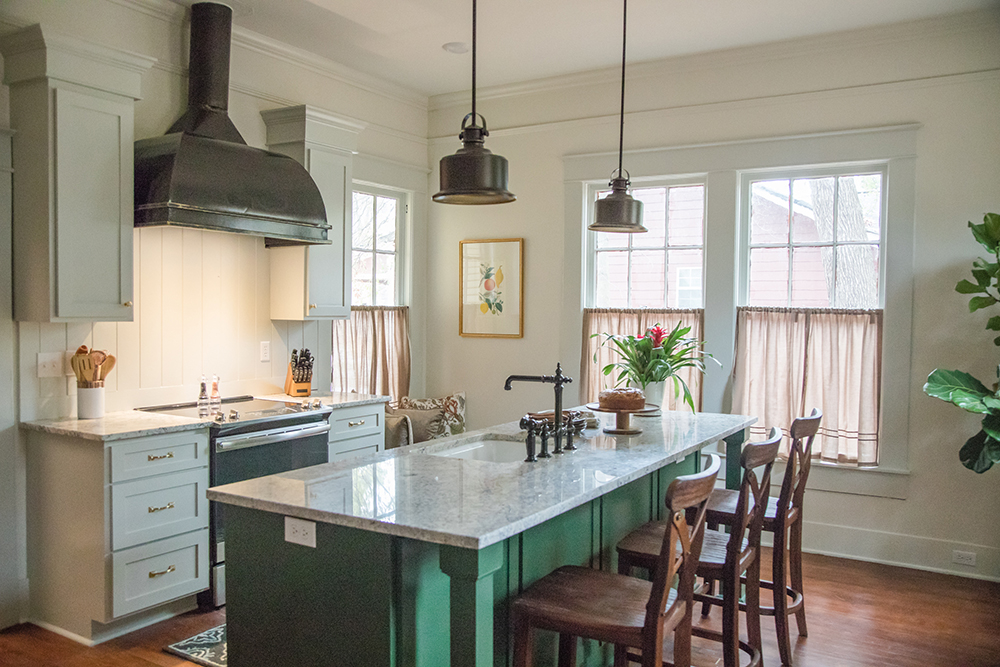 A country kitchen with rustic design and an emerald green island