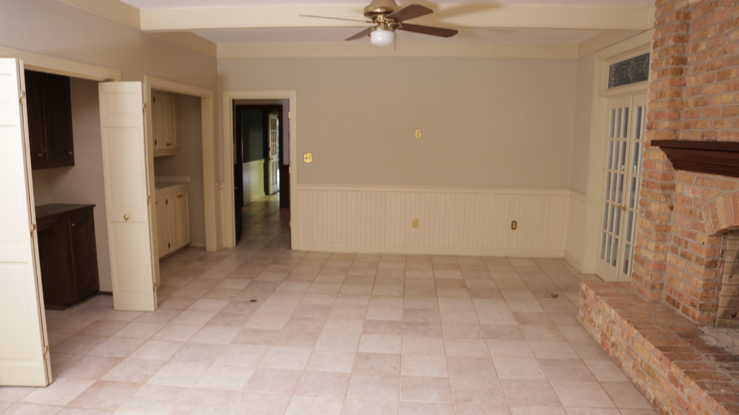 Empty family room with square tile floors and big brick fireplace