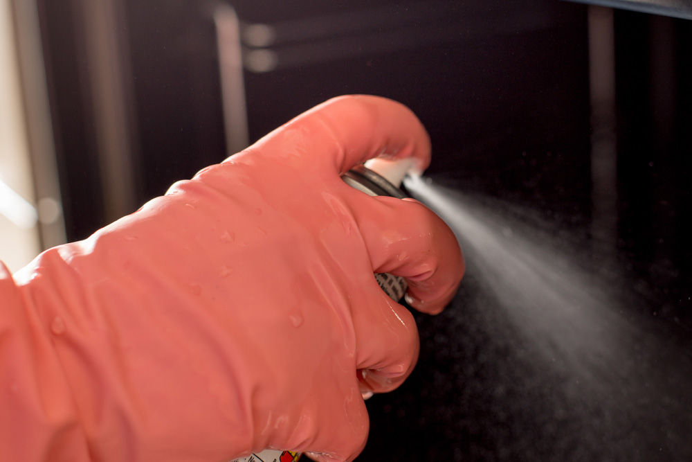 Gloved hand spraying cleaner