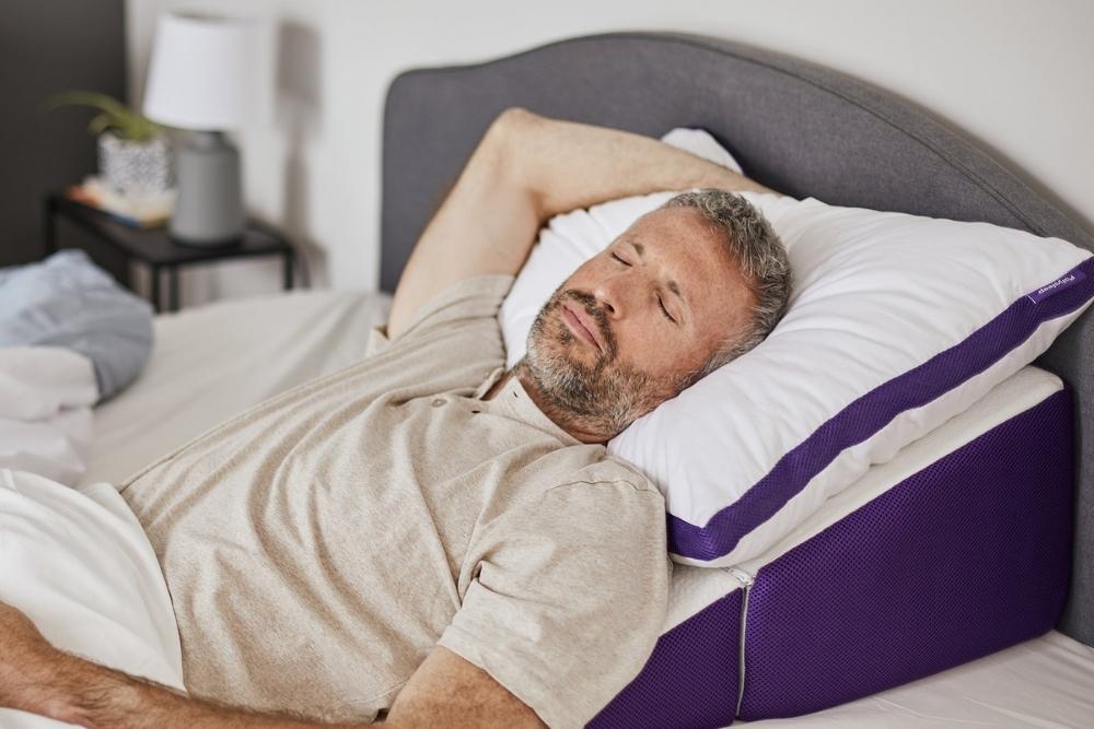 A middle aged man sleeping on the Polysleep Wedge pillow.