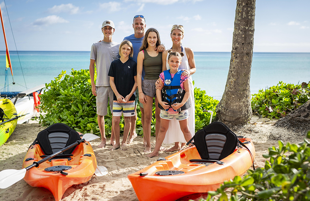 The Baeumler family post for a picture at the beach surrounded by kayaks.