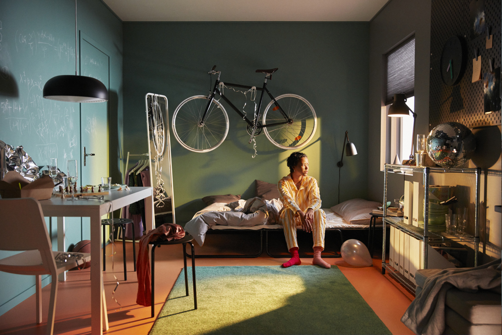 Woman sitting on bed with bike mounted on wall behind her