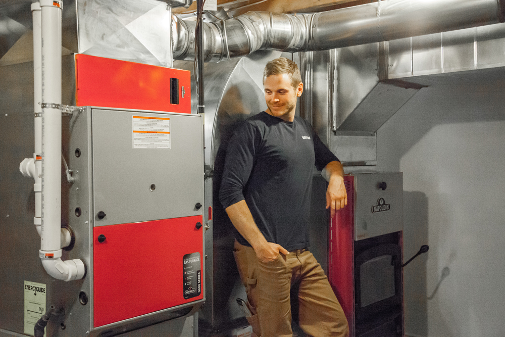 Mike Holmes Jr. in front of red and grey furnace