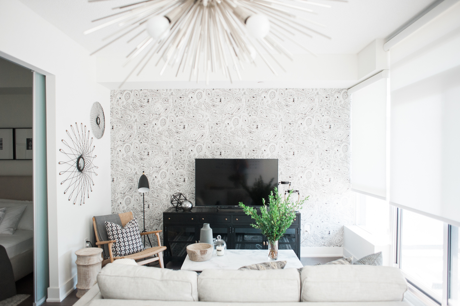 Modern white living room with black-and-white patterned accent wall.