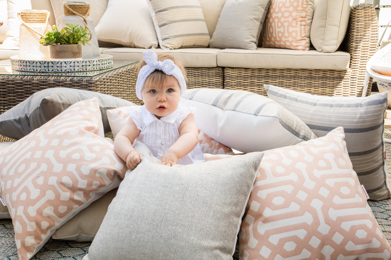 A baby playing among pillows