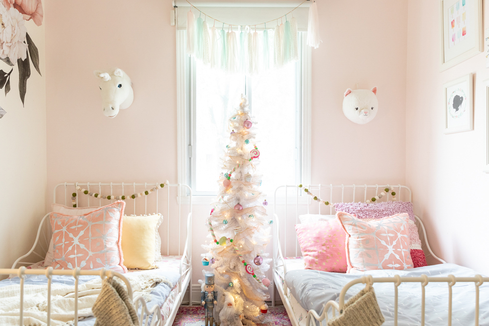 A tiny white Christmas tree stands between two single beds in the kids' bedroom