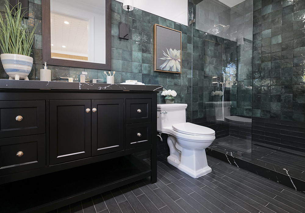 A bathroom with deep green tiles and black vanity