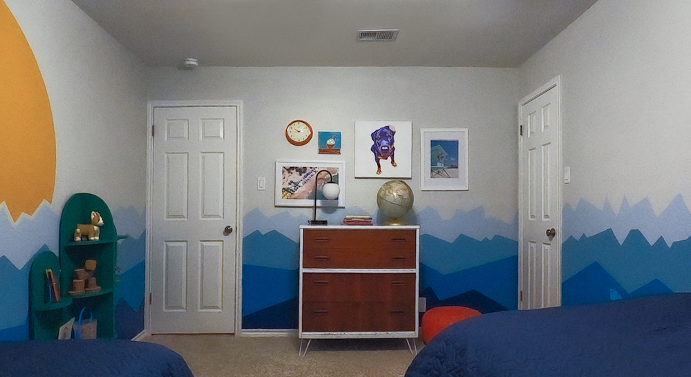 kids' room with wall mural, framed pictures on wall and wood dresser