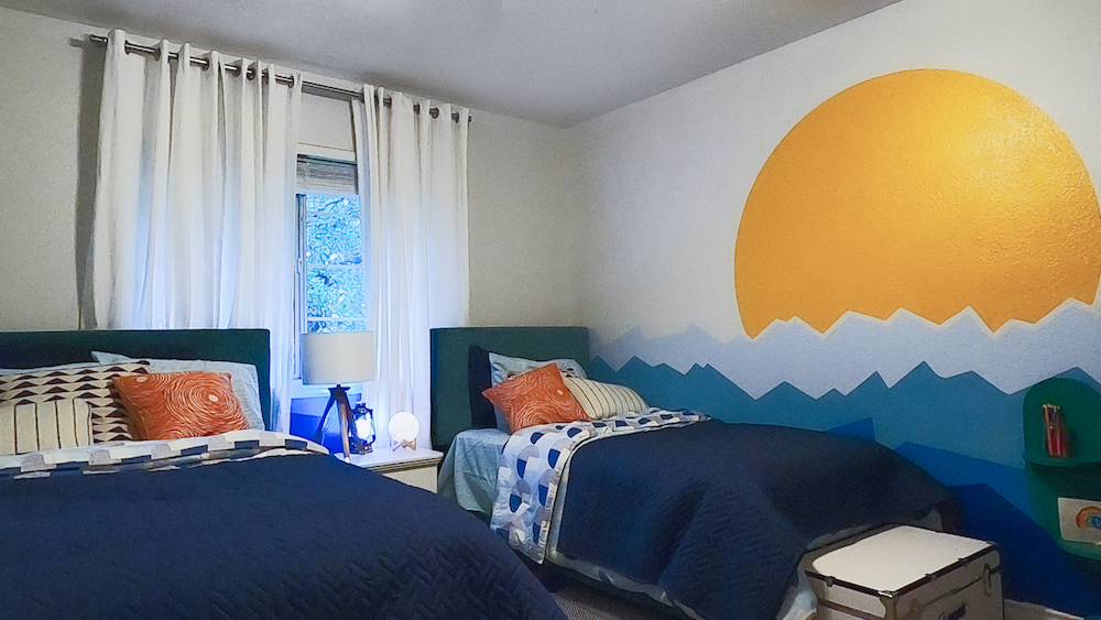 beachy kids' room with wave and sun wall mural and two beds