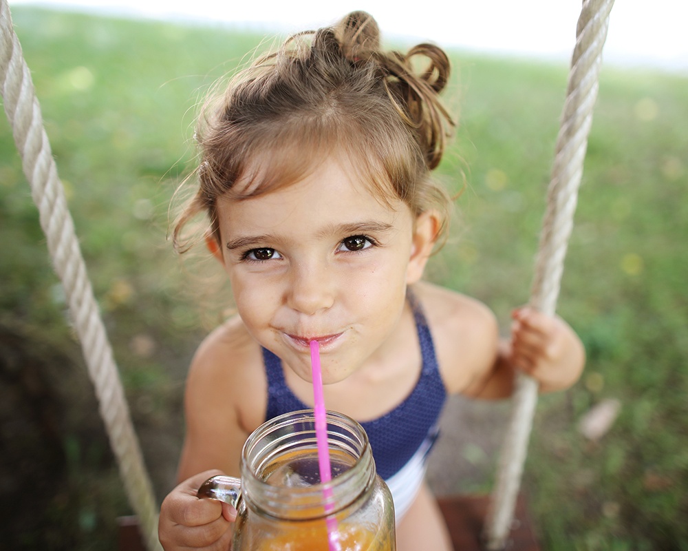 A young girl drinking on a swing