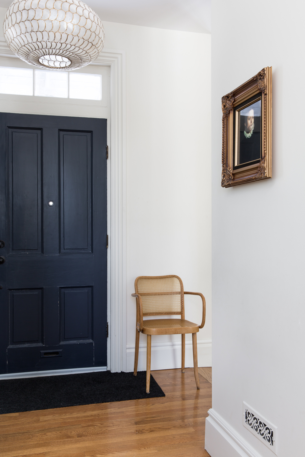 Entranceway to Parisian-inspired home with Thonet chair and gold-framed painting
