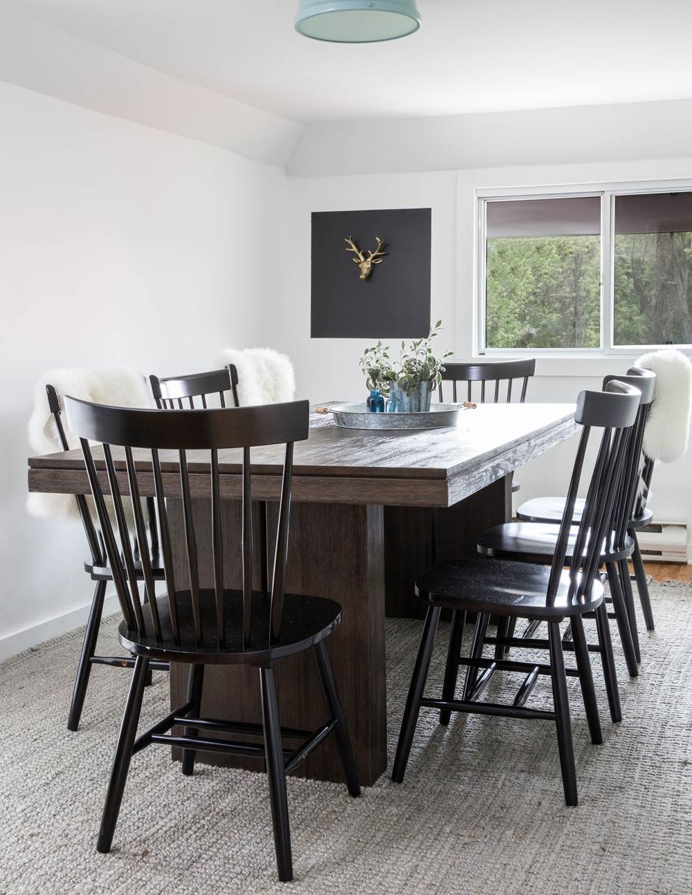 white dining room, brown table, black chairs, gold deer head art on black background