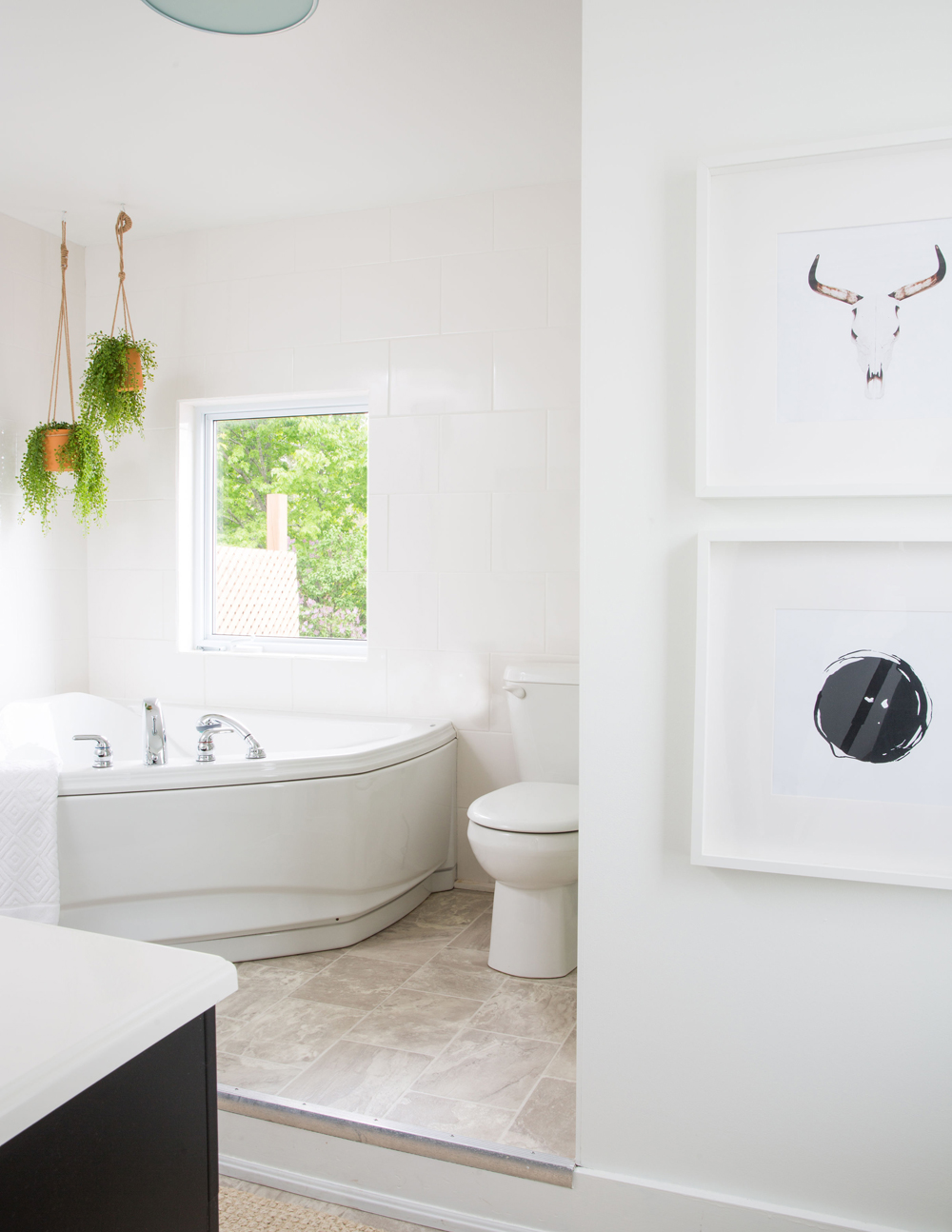 white bathroom with corner tub and two hanging plants above it