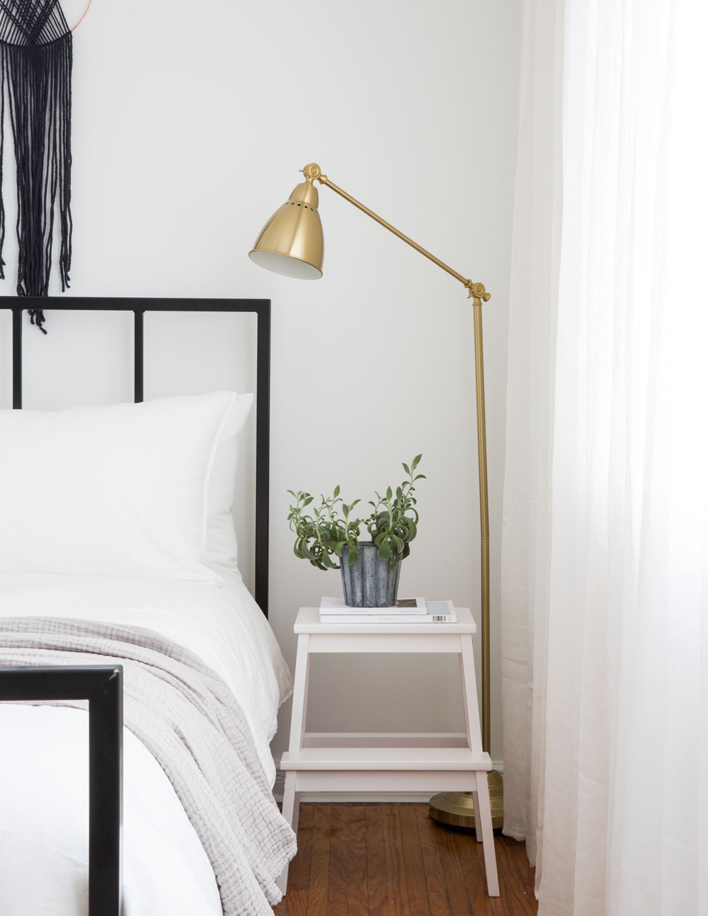 brass floorlamp beside white bed and white stool as sidetable