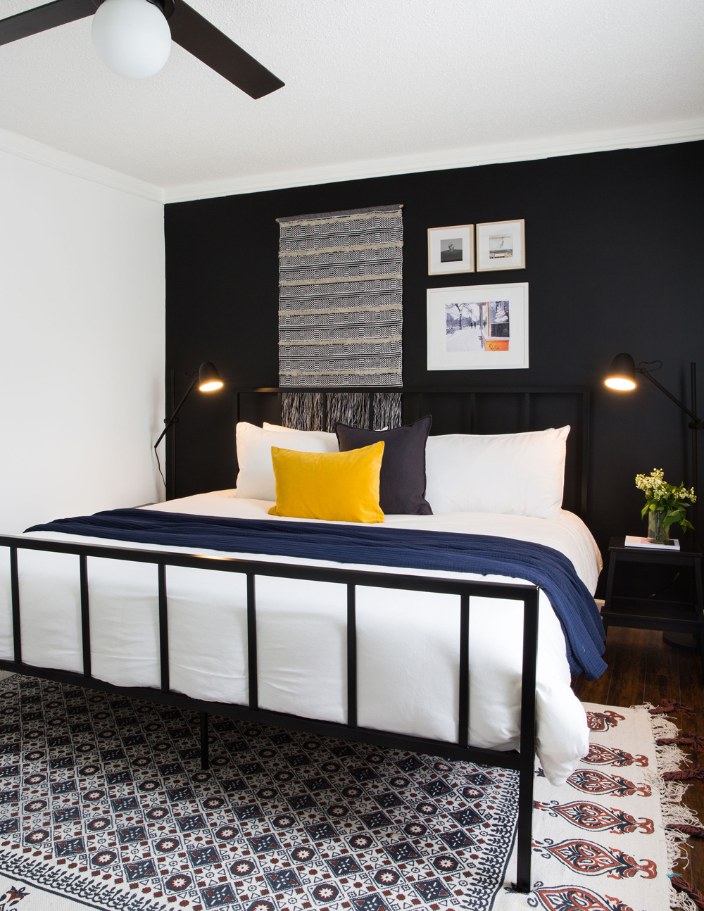 bedroom, black focal wall, art, blue throw on white bed, yellow and black toss cushions