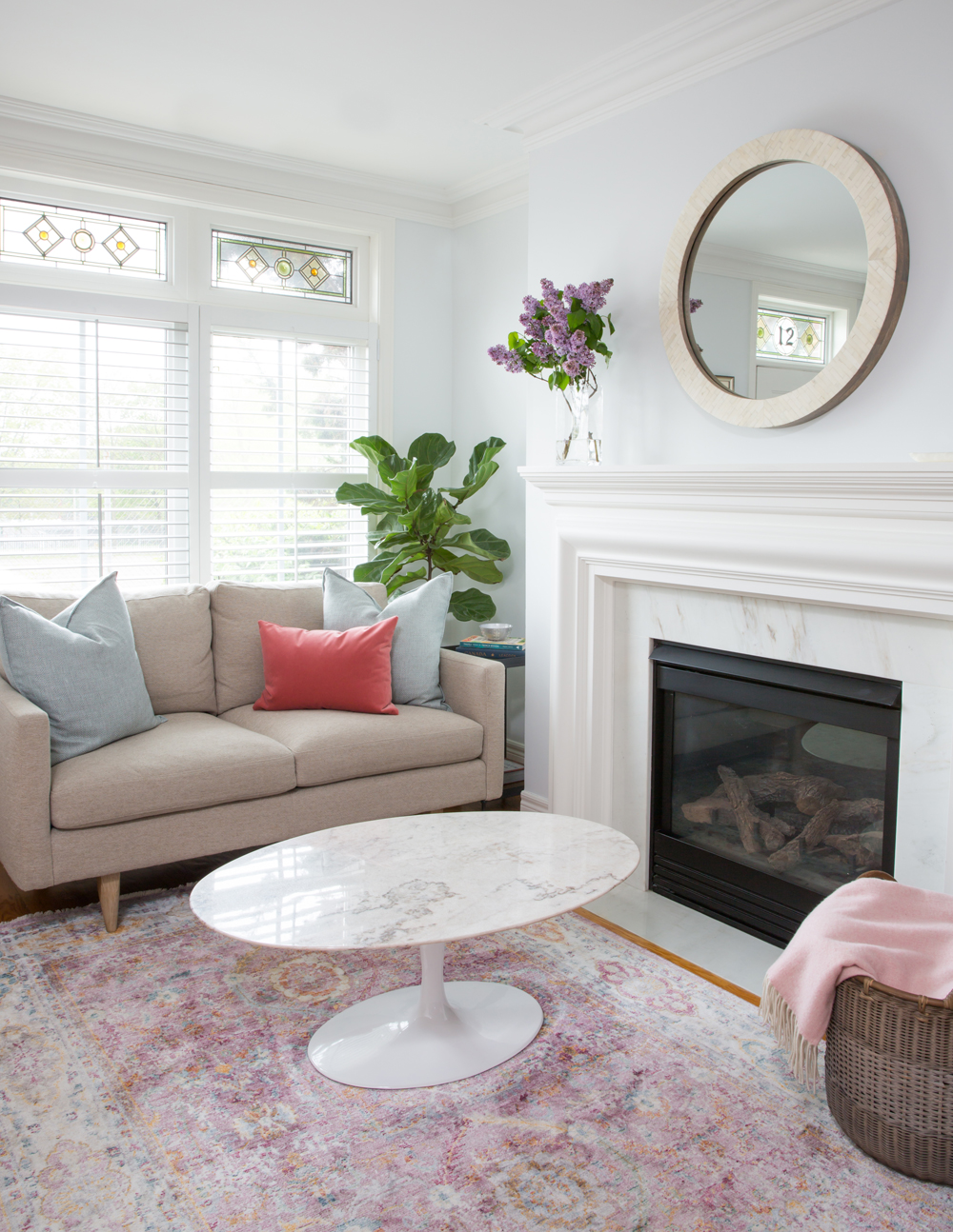 living room with fireplace, tan sofa, oval table and lilacs arrangement