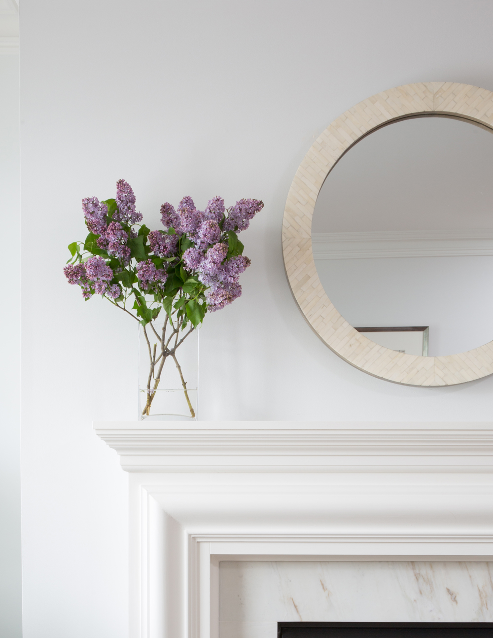 lilacs on mantel by round mirror