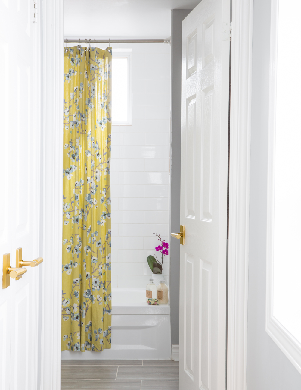 bathroom door open to yellow and white floral shower curtain
