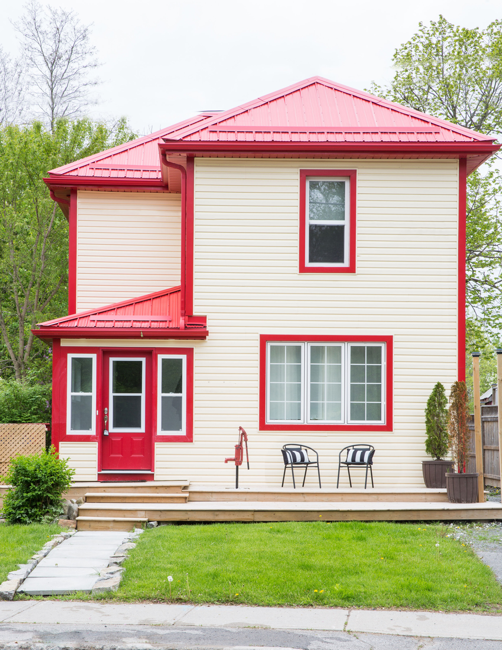 tan siding house exterior with red trim and front lawn