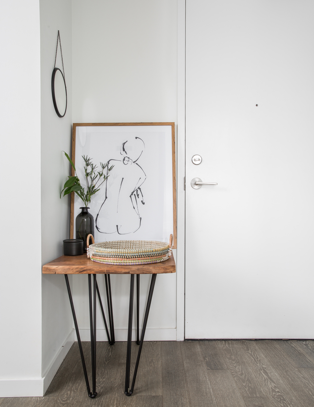 white condo entry door with line drawing of woman and wood topped black leg table