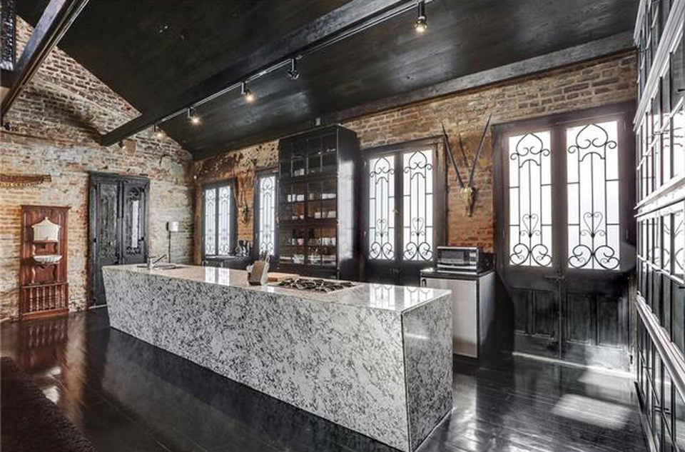 An open-concept kitchen with exposed brick and marble island