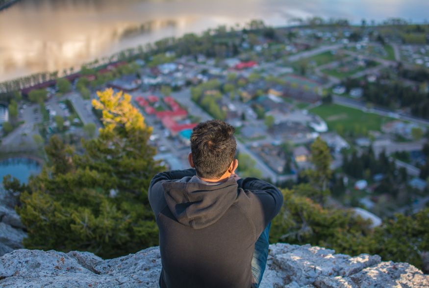 A man perched on a rock overlooking the city of Lethbridge, Alberta